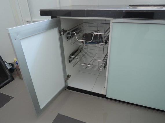 Kitchen cabinet with pull-out wire baskets; white doors, dark countertop, open cabinet.