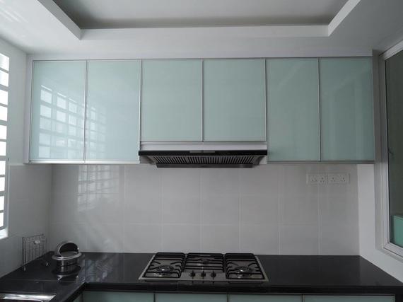Kitchen with light blue glass-fronted cabinets above a stove, black countertop, and white tiled backsplash.
