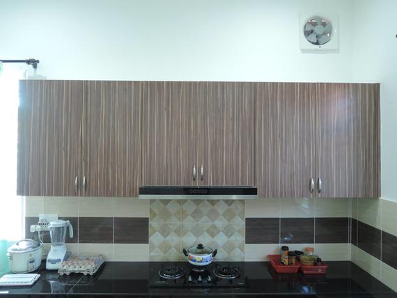 Kitchen with brown striped cabinets, black countertop, and tiled backsplash.