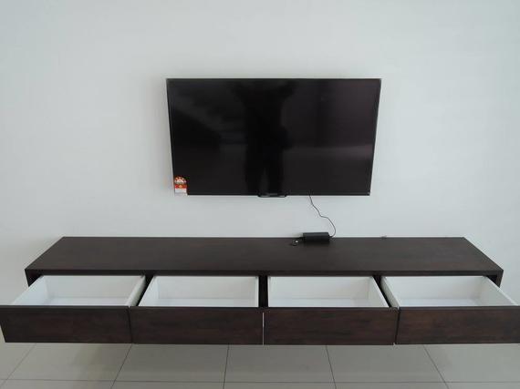 A dark brown floating media console with four open white drawers under a wall-mounted TV.