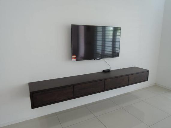 A flat-screen TV mounted above a dark wood floating media console on a white wall.