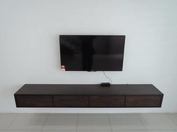A flat-screen TV mounted above a dark wooden floating cabinet against a white wall.