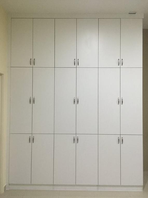 White floor-to-ceiling storage cabinets with multiple doors and silver handles in a room.