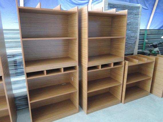 Wooden bookshelves of varying sizes, empty, in a light brown color. They have open shelves.
