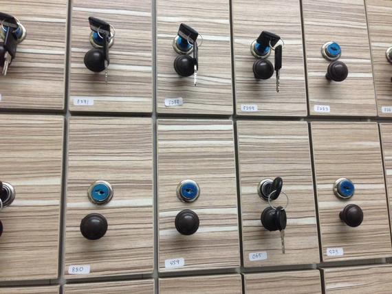 Display of cabinet locks with keys on wooden panels.