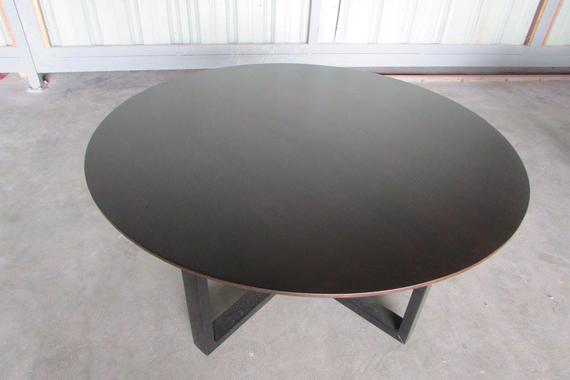 Round black coffee table with dark angular legs.