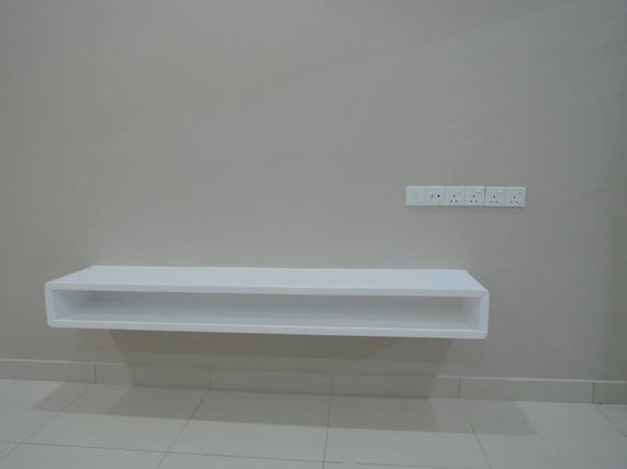 White floating shelf on a beige wall, near a power outlet.