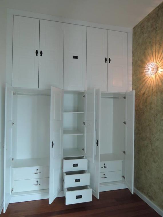 White built-in closet with open doors showing drawers, shelves, and hanging space.