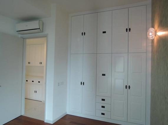 White built-in closet with black handles. Air conditioner over the door. Entryway to another closet.
