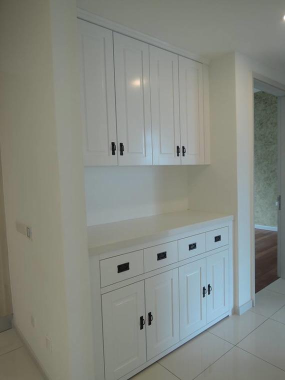 White built-in storage cabinet with upper doors, countertop, drawers, and lower doors; located in a room.