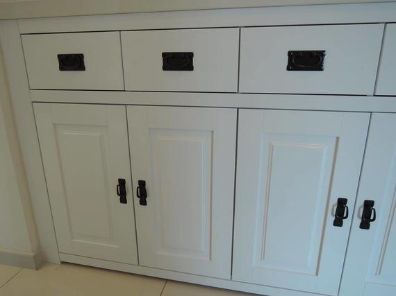 White cabinet with three drawers and three doors, black handles.