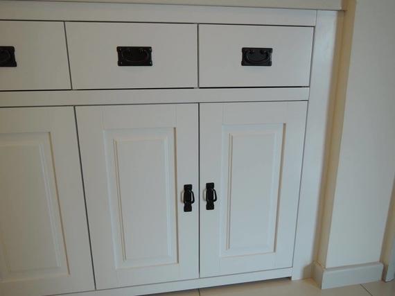White cabinet with drawers and doors, black hardware.