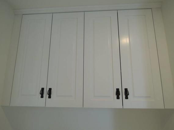 White overhead cabinets with dark handles.
