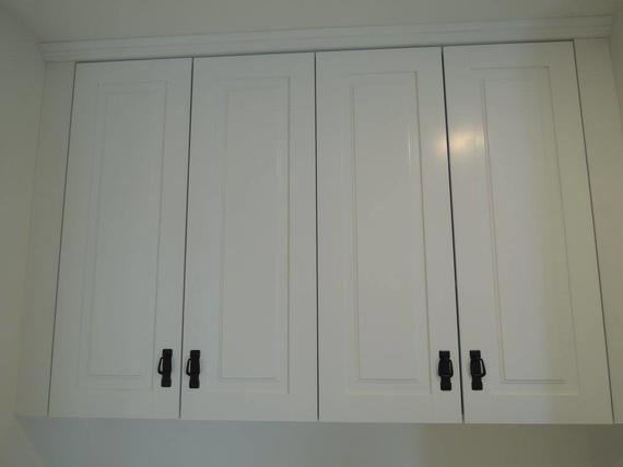 White cabinets with black handles above a shelf.