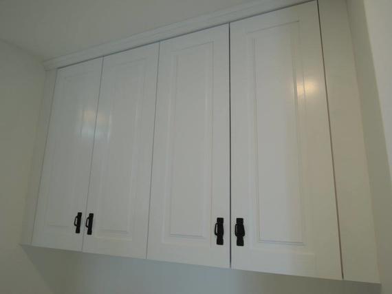 White cabinets with black handles mounted above a white surface.