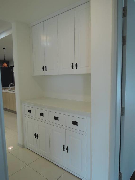 White built-in cabinet with black handles, countertop, and drawers in a hallway.