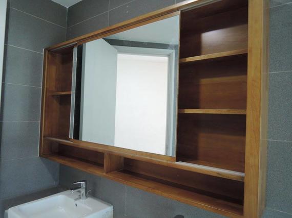 Wooden medicine cabinet with sliding mirror, shelves, and sink below.