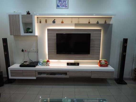 A modern living room entertainment center with a mounted TV, storage, and lighting.
