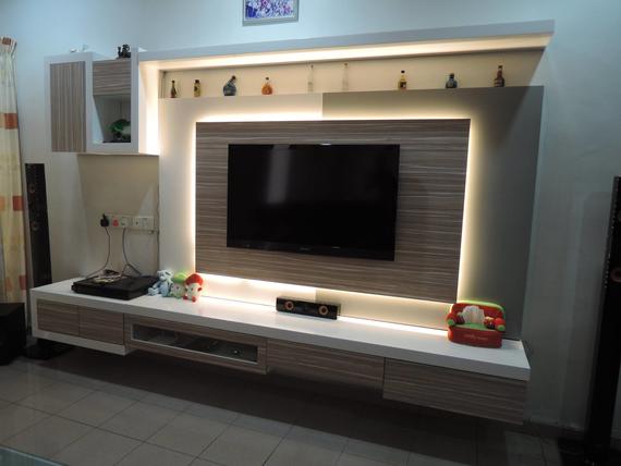 Modern TV wall unit with built-in lighting and cabinetry; TV mounted, speakers on sides.