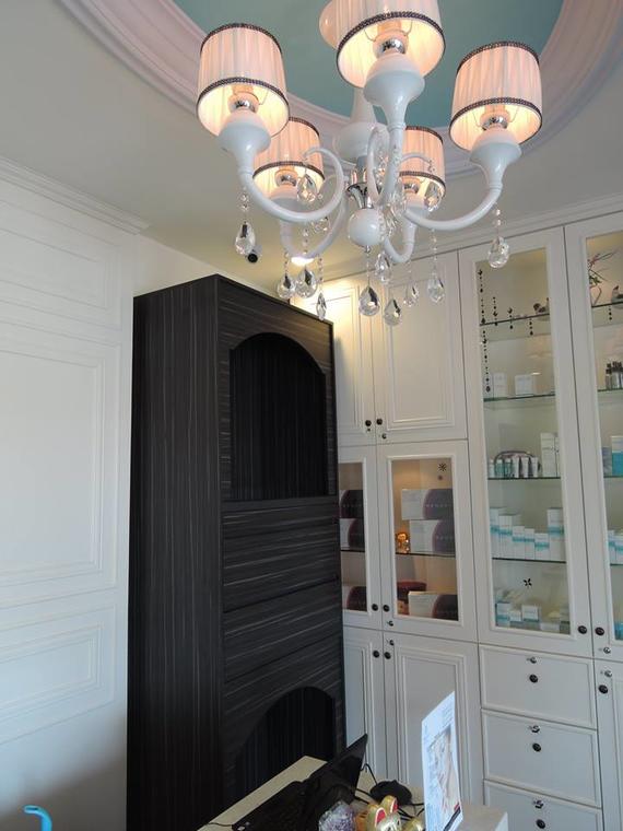 Chandelier above a dark cabinet in a white-walled room with a built-in display cabinet.