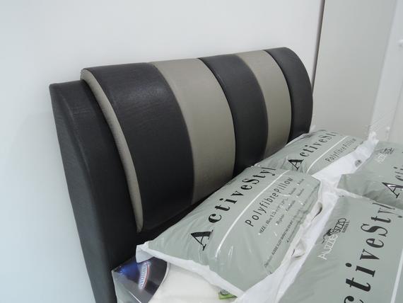 Black and gray striped bed headboard; pillows are stacked in front of it.