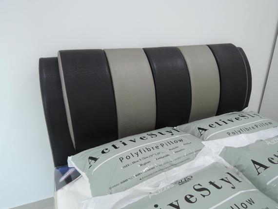 Black and gray striped headboard with packaged pillows in front.