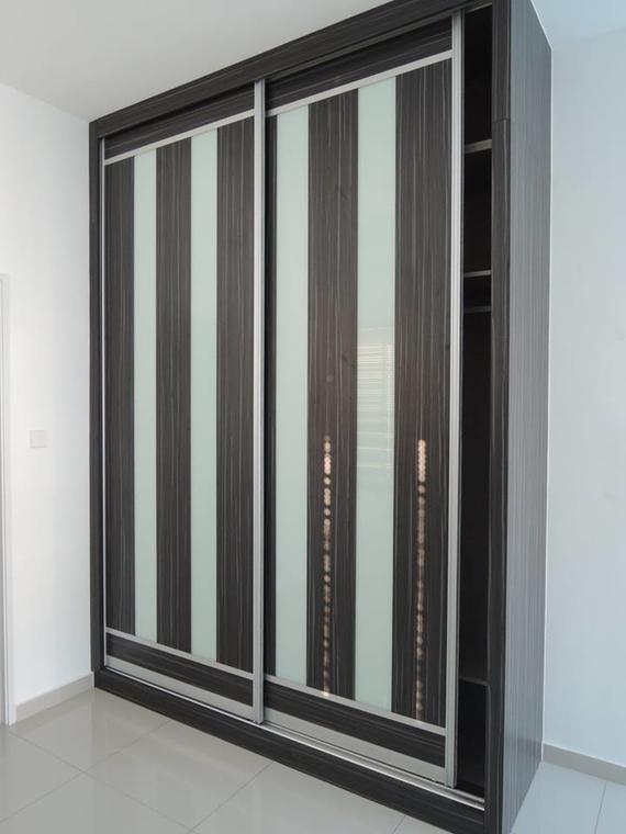 Dark wood closet with vertical stripes of light and dark colors. Sliding doors with long gold handles.