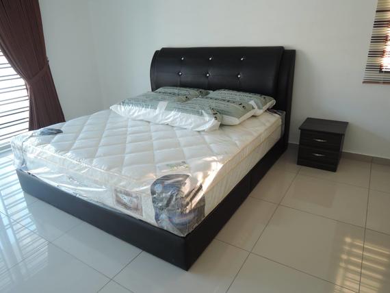 A black bed with a headboard, mattress in plastic, pillows, and a nightstand in a well-lit room.