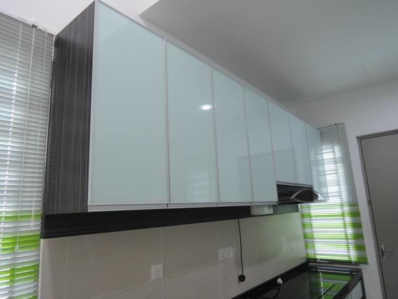 Kitchen with white-glass front cabinets, dark wood trim, and range hood above a countertop.