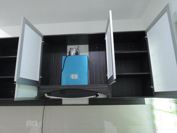 Kitchen cabinets with open doors revealing a blue appliance, above a range hood.