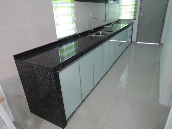 Long, modern kitchen island with black countertop and light blue cabinets.