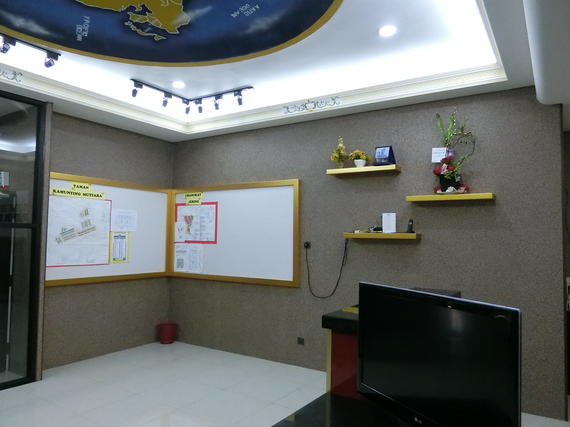 Corner office with whiteboard, TV, shelves, and a globe ceiling, lit by track lighting.