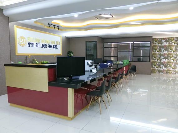 Reception area with red, gold, and black desk, chairs, and company sign.