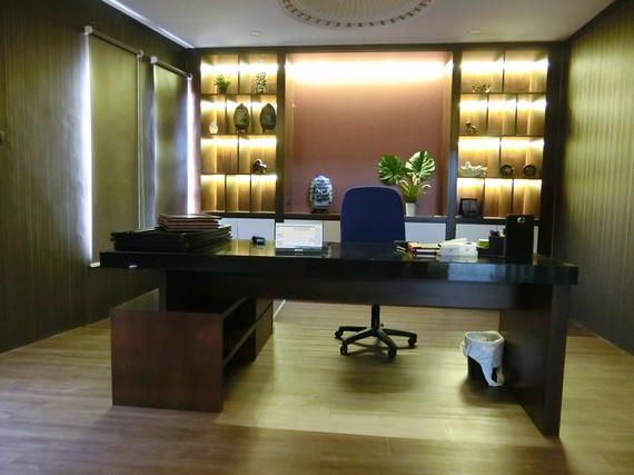 Executive office with desk, shelving, chair, and a plant. Dark wood and warm lighting.