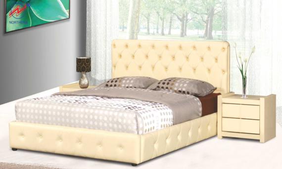 Cream-colored bed with tufted headboard and frame, nightstand, lamp, and flowers in a bright bedroom setting.