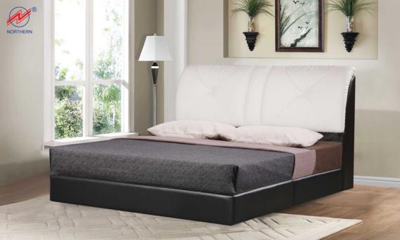 Black and white bed in bedroom setting.  Features a white headboard and dark gray bedspread.