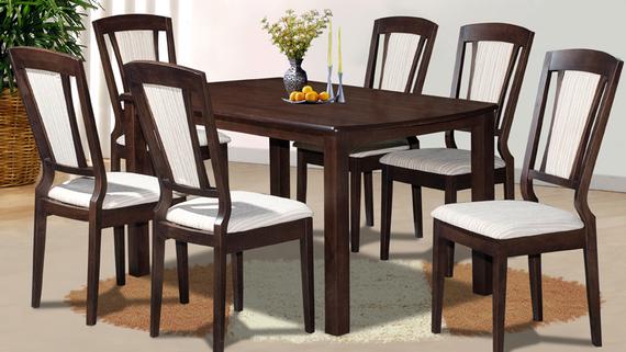 Dark wood dining table and chairs, set for a meal. White cushioned seats, flowers in the center.