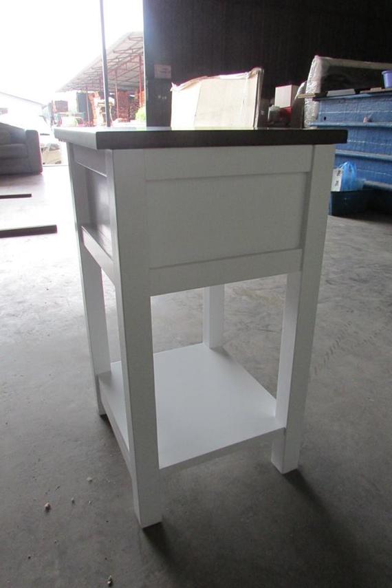 White and brown wooden nightstand with a drawer and shelf in a workshop setting.