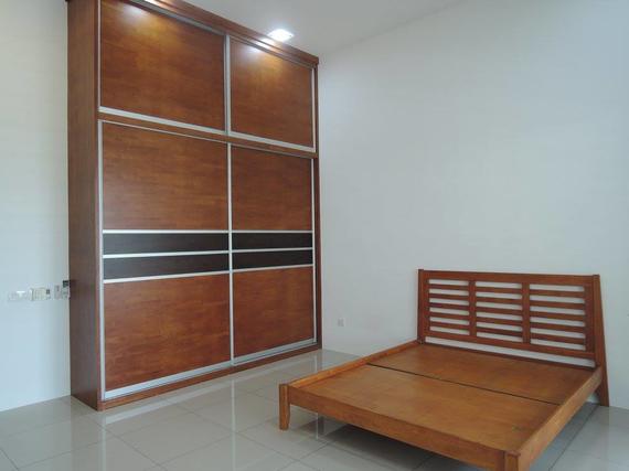 Wooden wardrobe and bed in a room with white walls and tile floor.