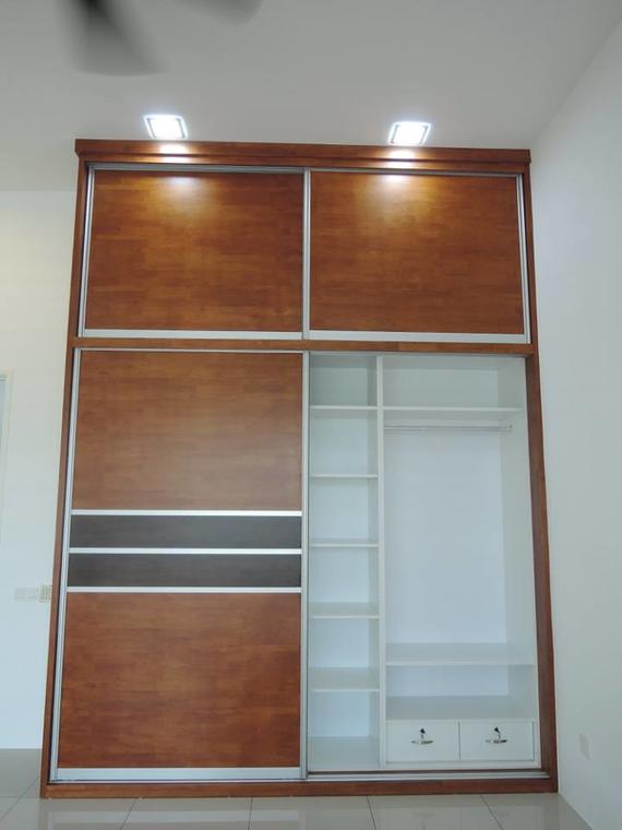 Wooden sliding door wardrobe, one door open revealing shelves, drawers, and hanging rod, illuminated by ceiling lights.