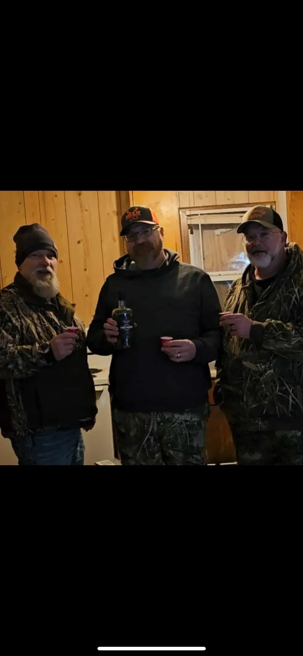 Three men are standing next to each other in a room.