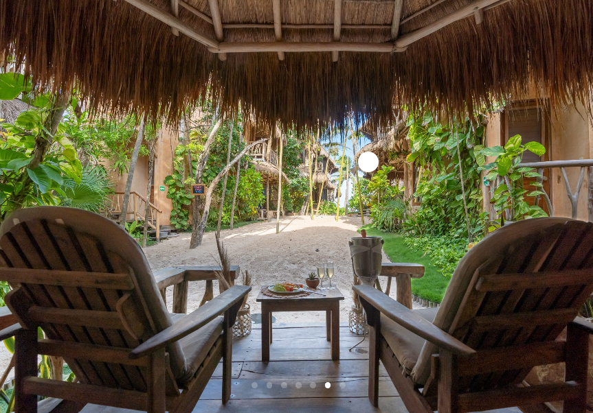 A dining room with a table and chairs and candles lit up at night.