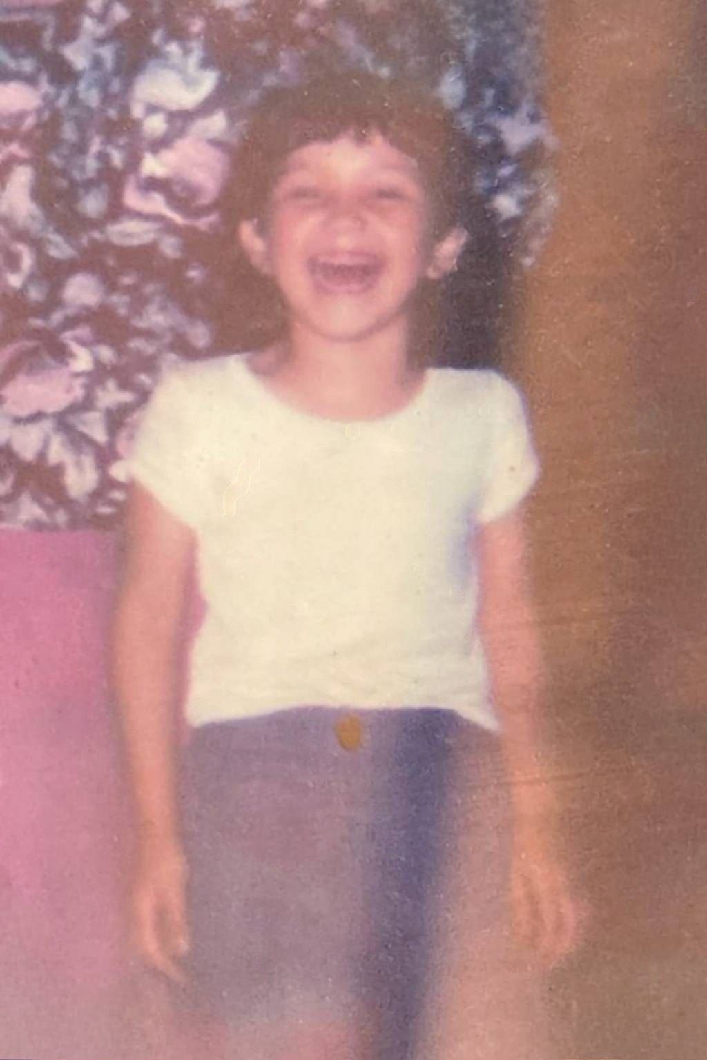 a young girl in a white shirt and shorts is laughing .