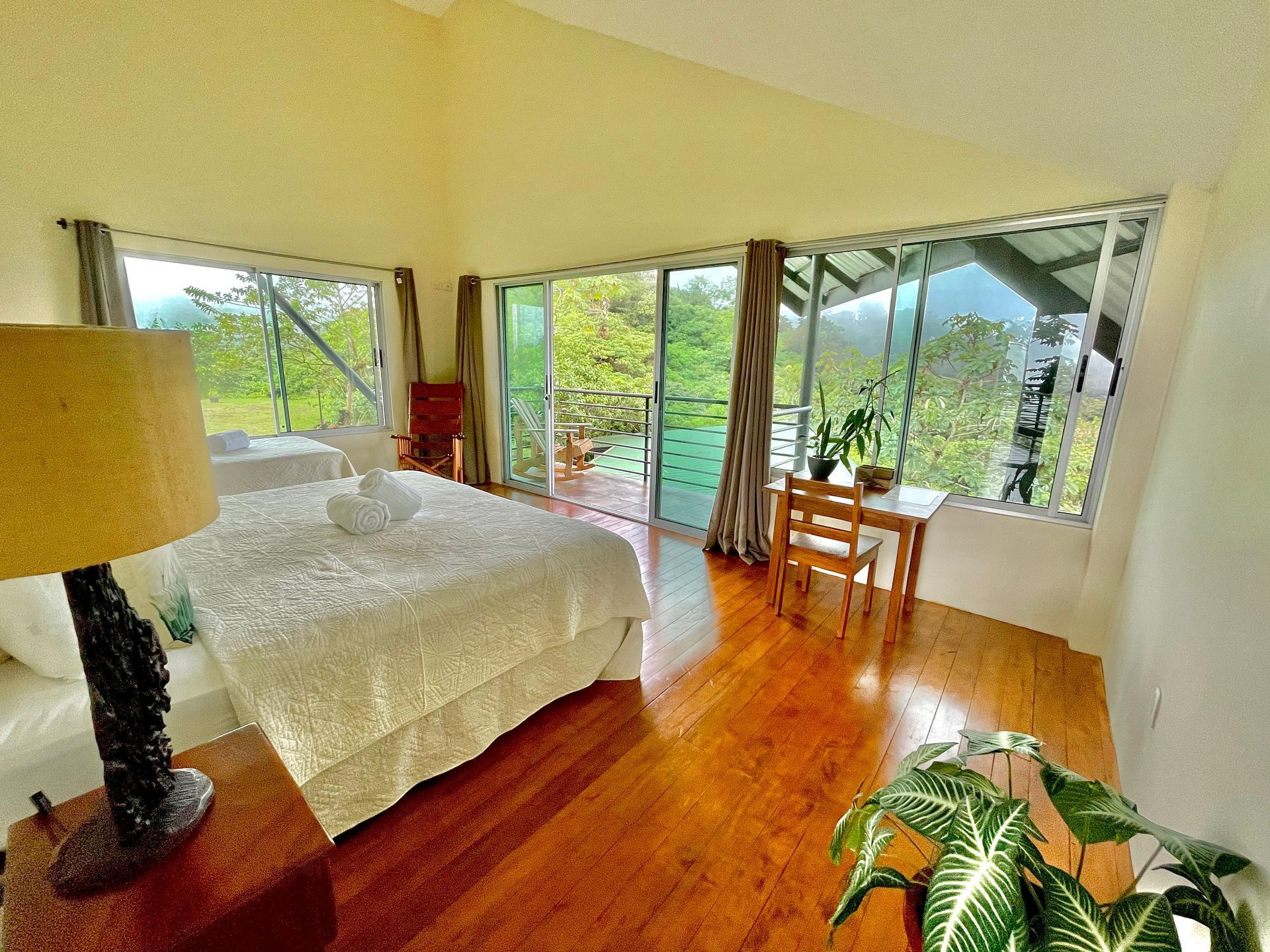 A bedroom with a large bed , a lamp , a table and chairs.