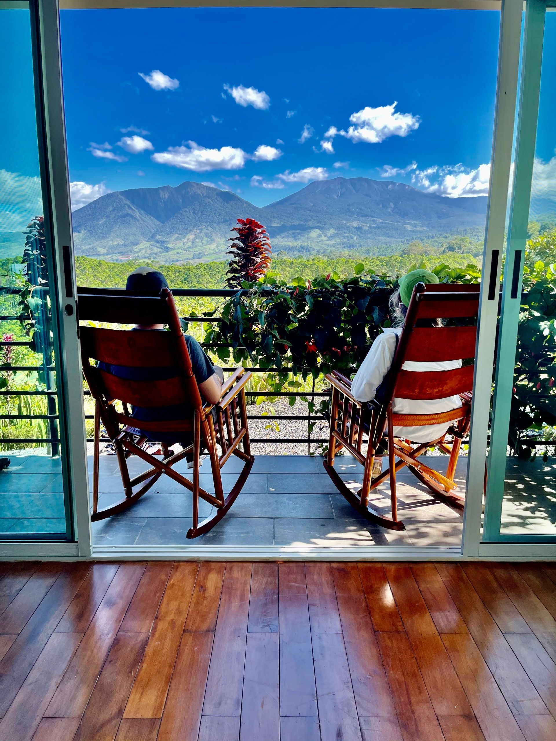 Two rocking chairs are sitting on a balcony overlooking mountains