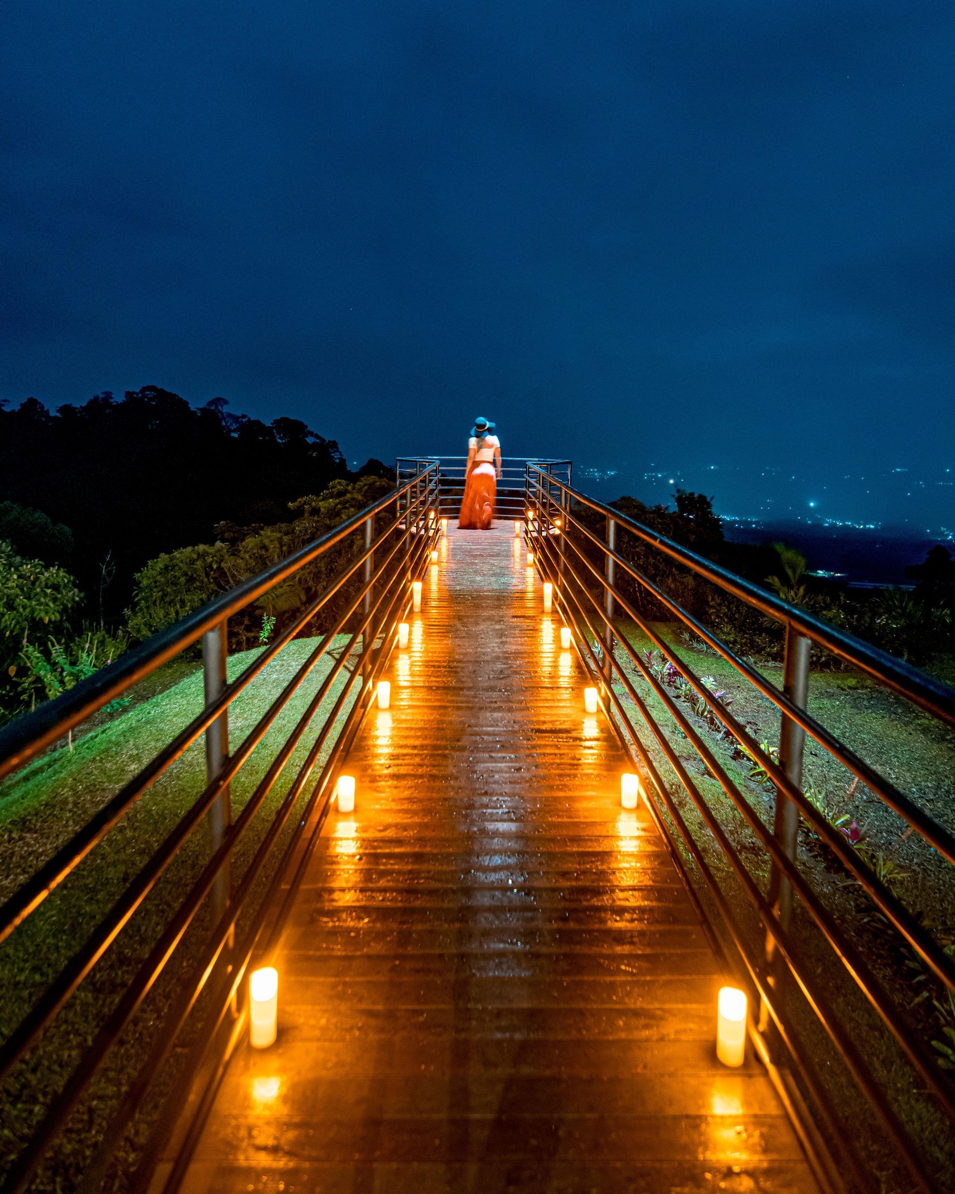 A wooden walkway with candles on it at night