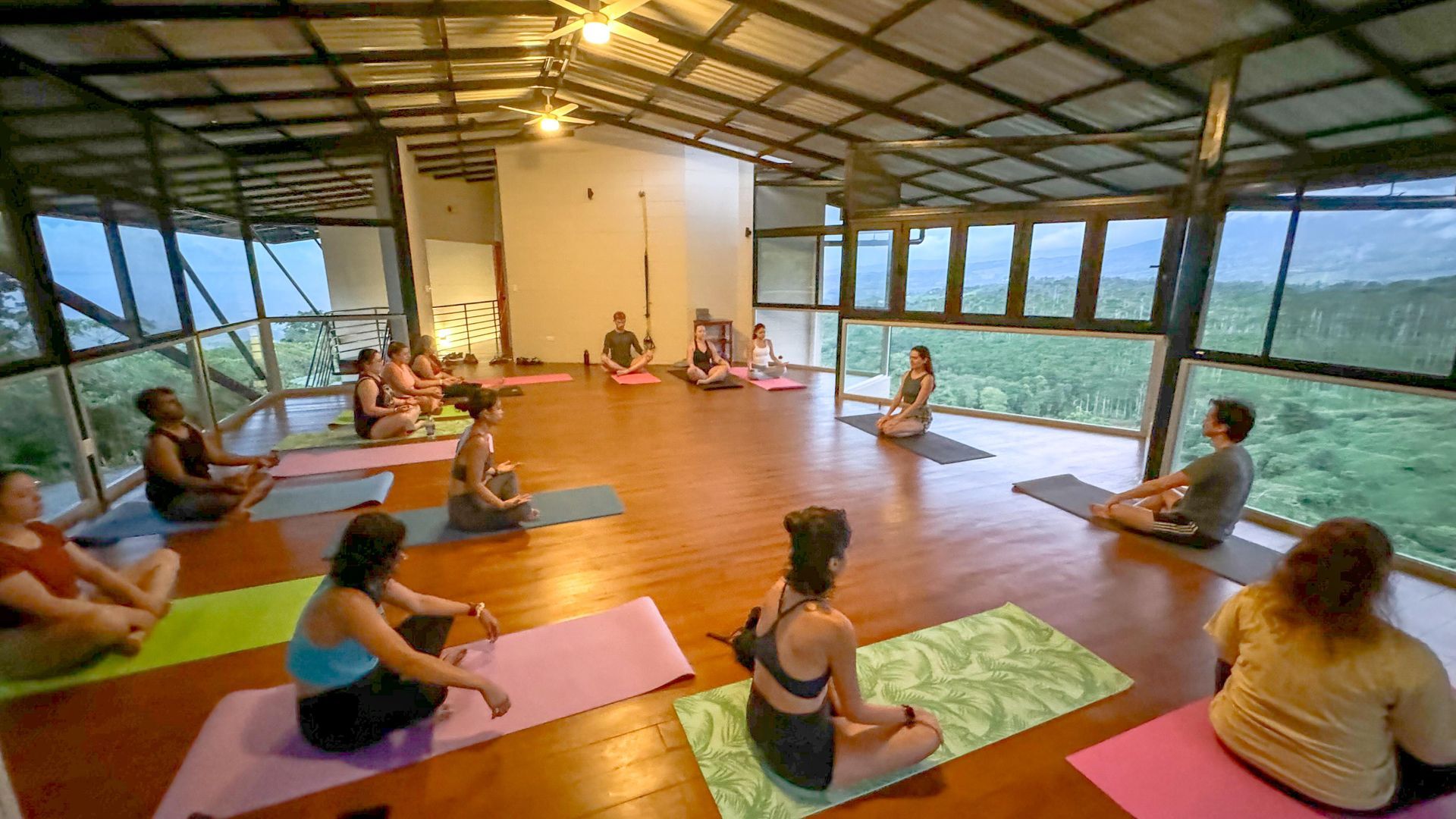 A group of people are sitting on yoga mats in a room.