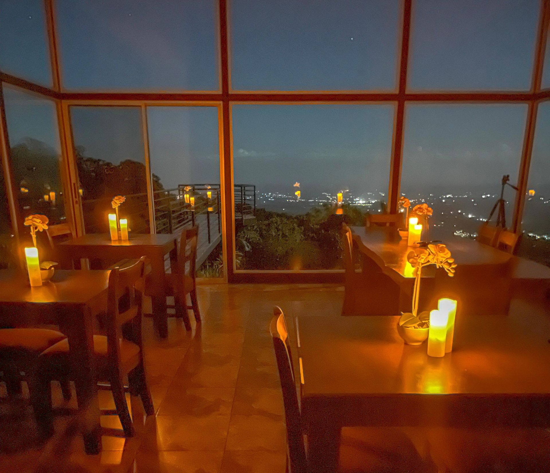 A restaurant with tables and chairs and candles on them at night