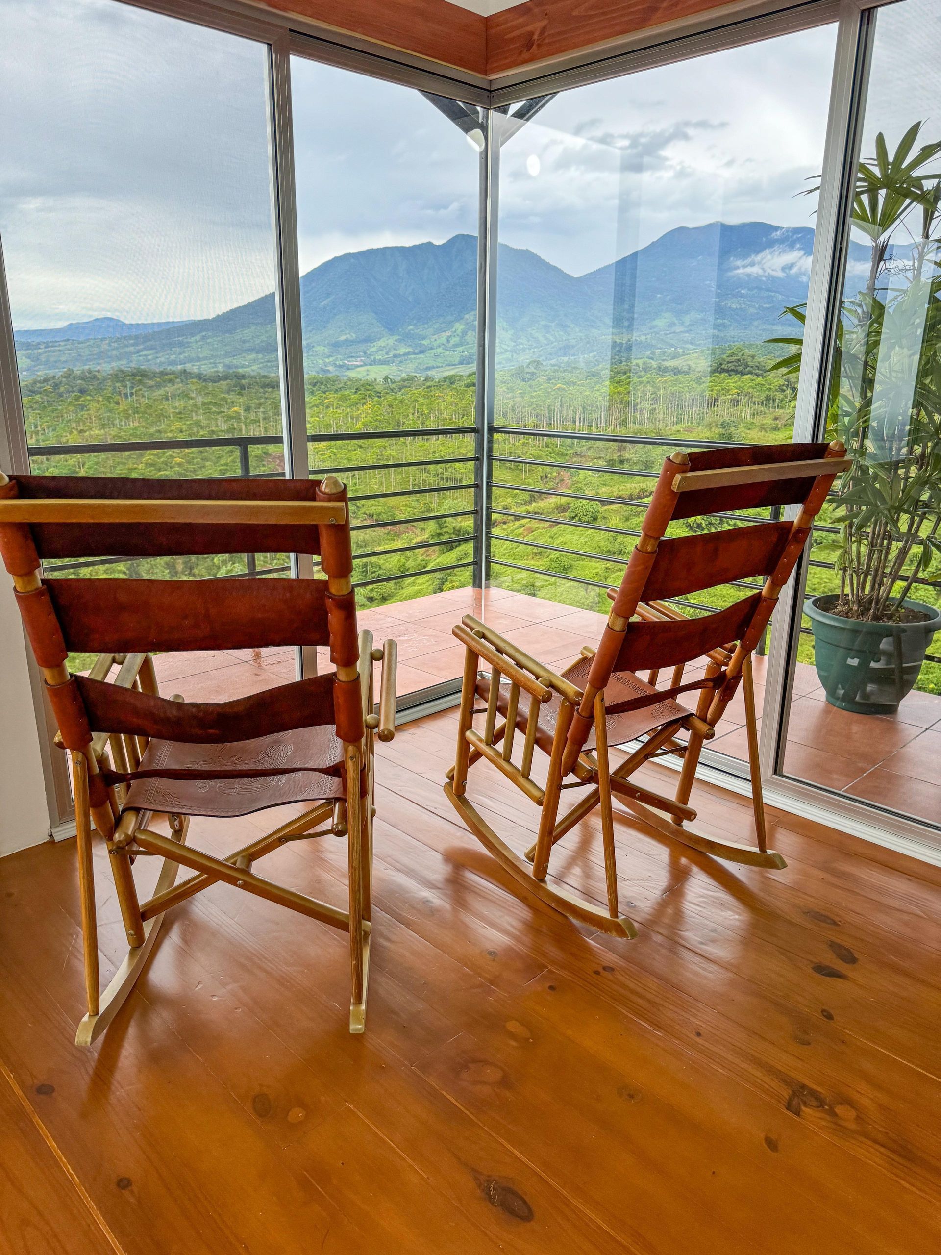 Two rocking chairs are sitting in front of a window with a view of mountains.