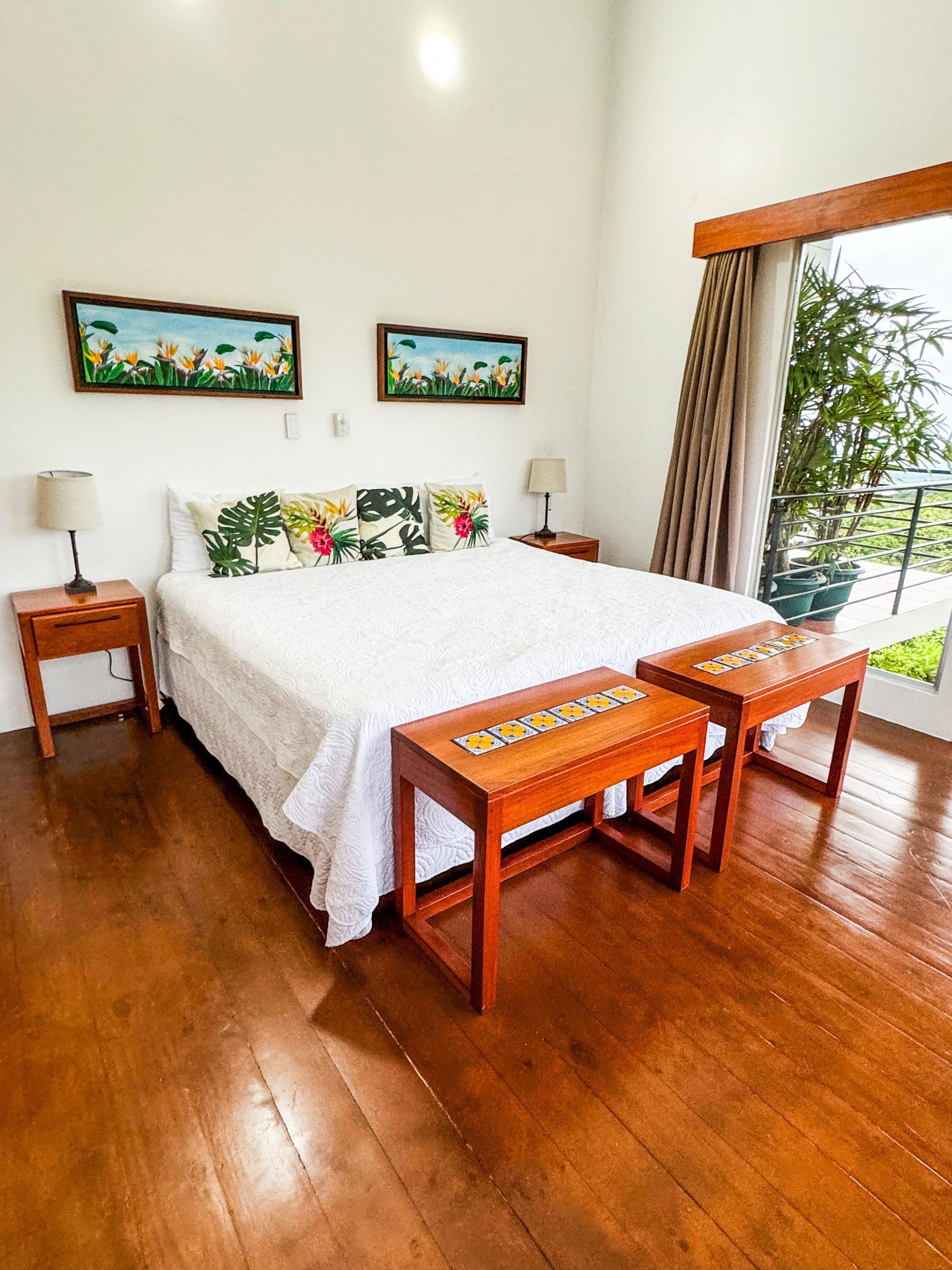 A bedroom with a large bed , two benches and a window.
